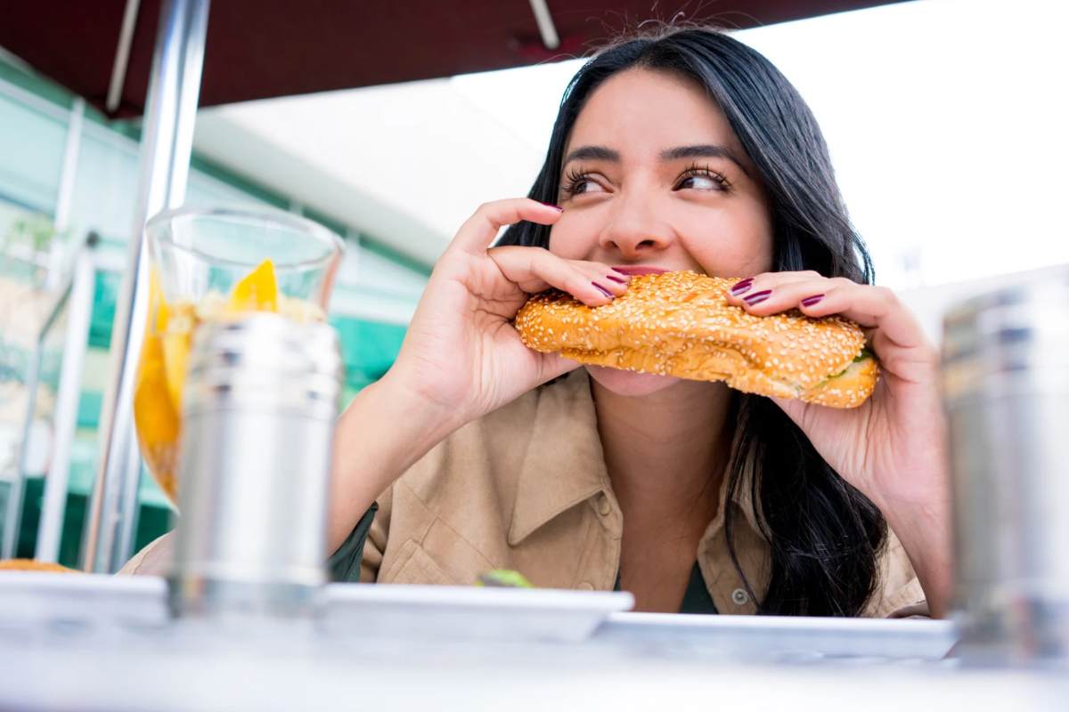 Donna seduta che addenta un panino