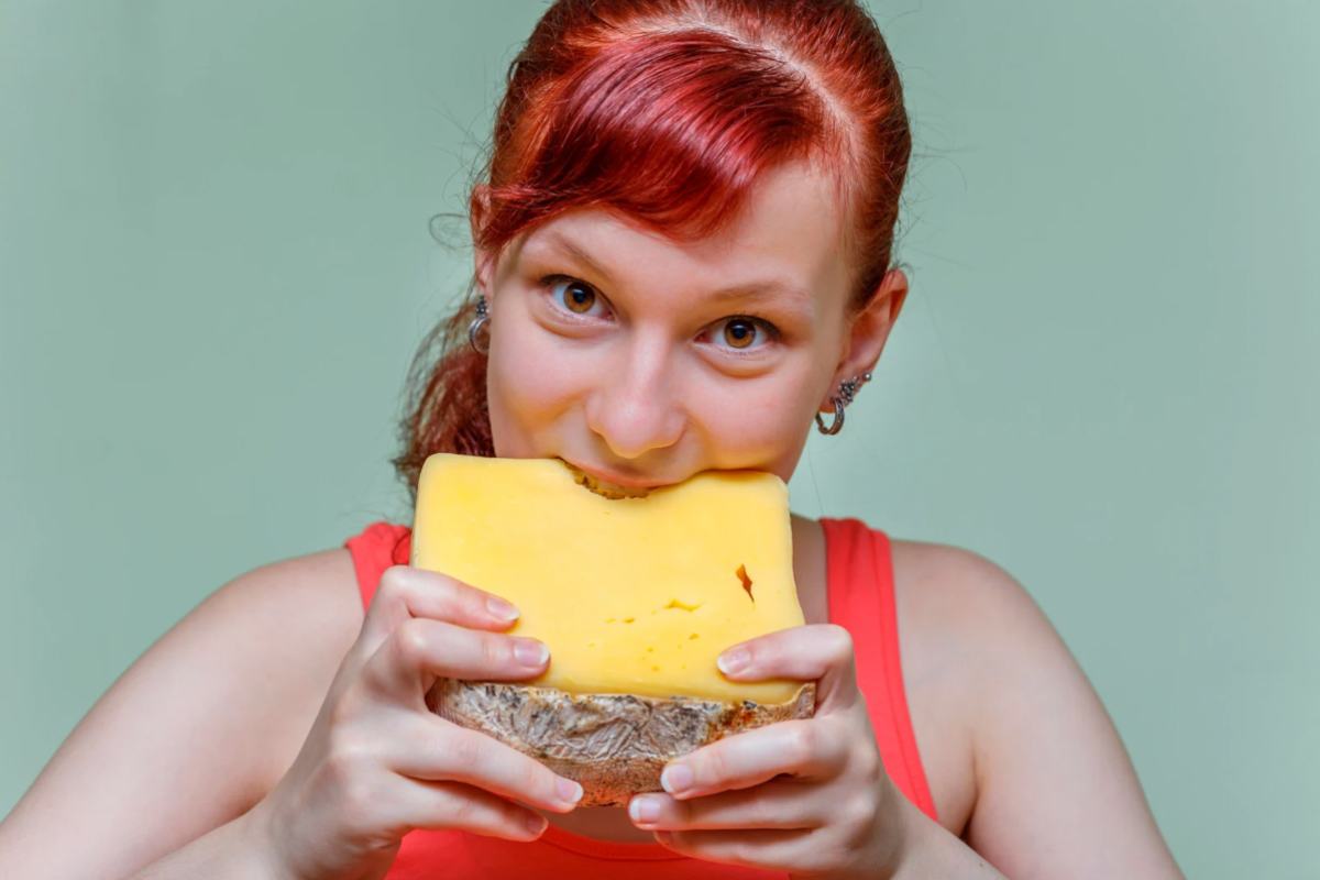 Donna rossa che mangia una fetta di formaggio