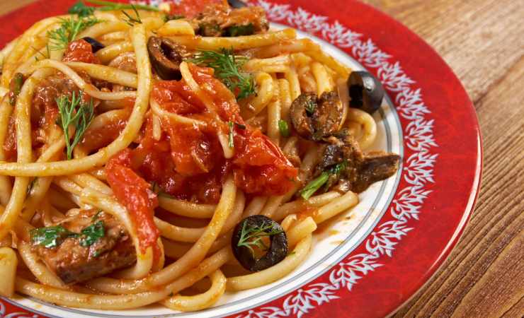 pasta alla puttanesca con tonno in piatto bordato di rosso