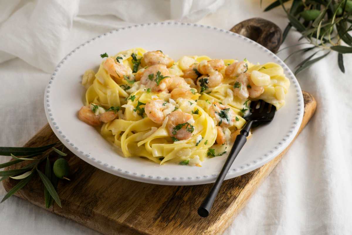 pasta con zucchine e gamberetti in piatto bianco