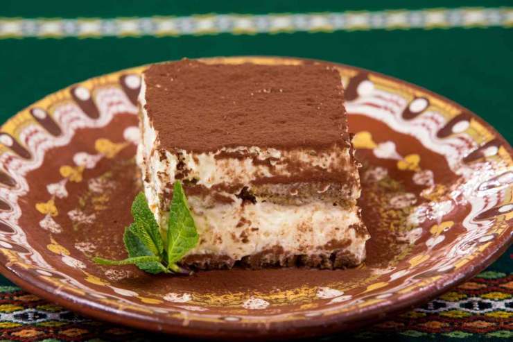 fetta di tiramisù in un piatto con una fogliolina di menta