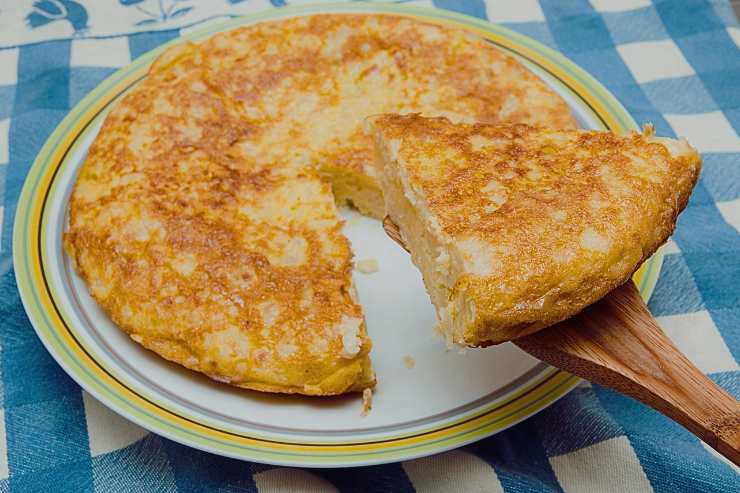 Frittata nel piatto con fetta su mestolo di legno