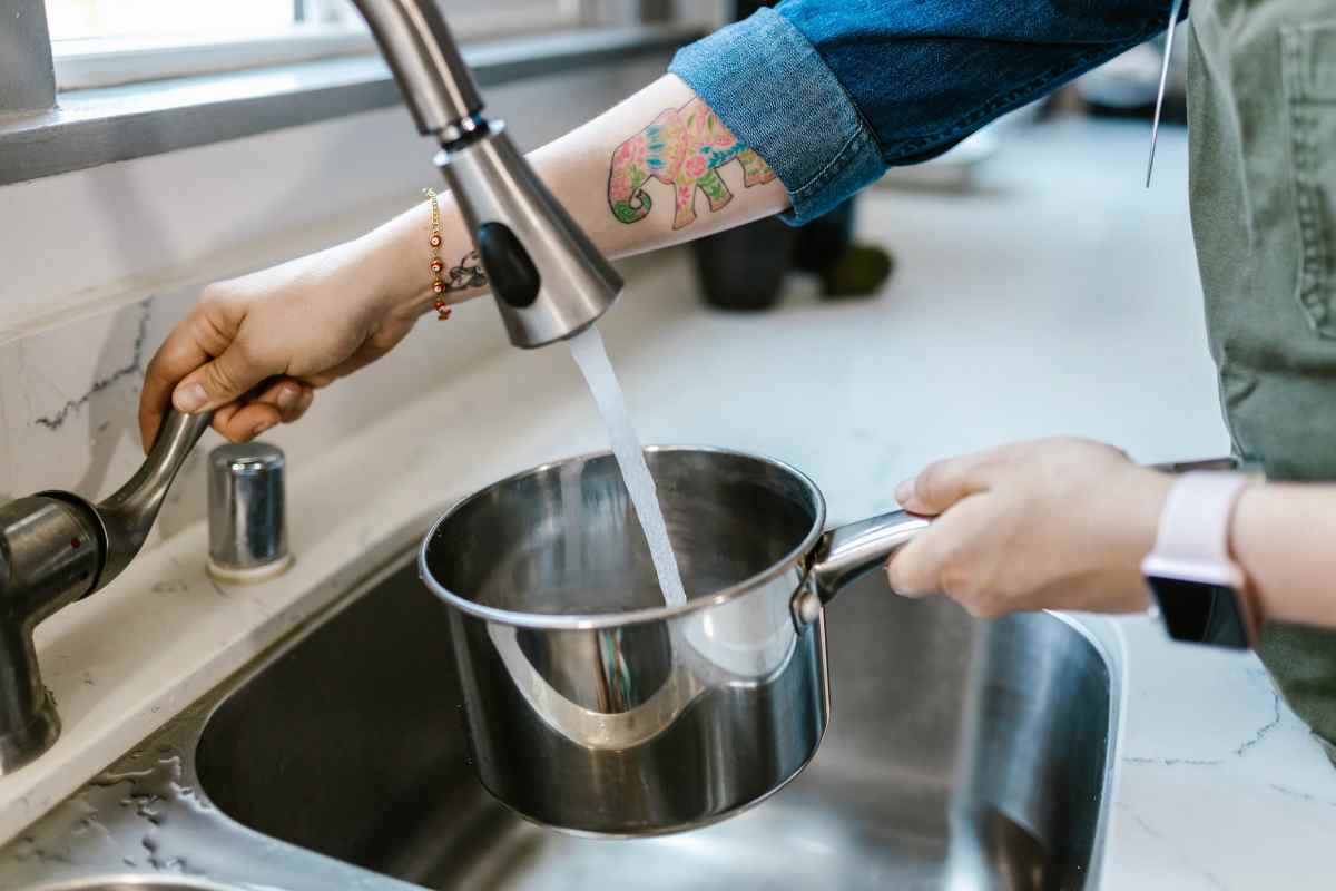 donna che riempie pentola con l'acqua