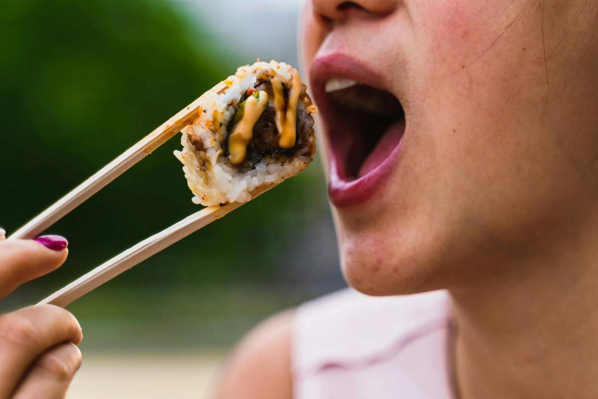 Donna che mangia un boccone di sushi